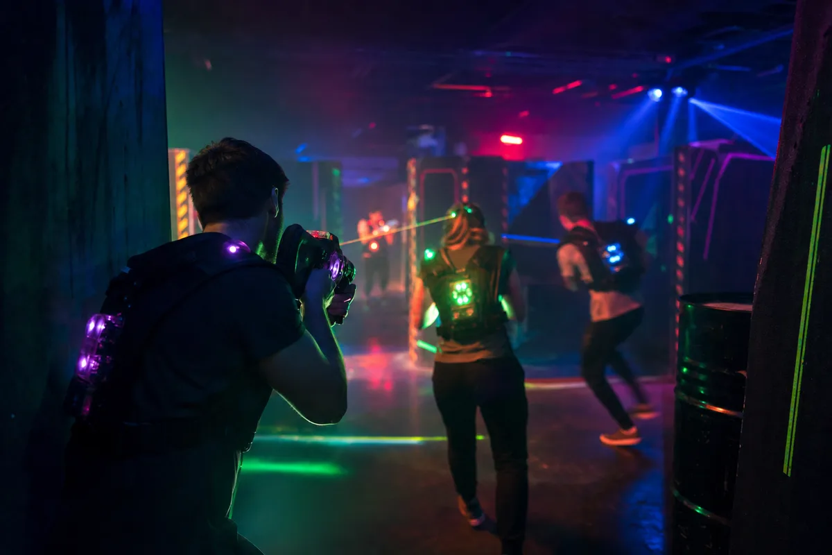 Amis en pleine partie de laser game dans une arène aux néons