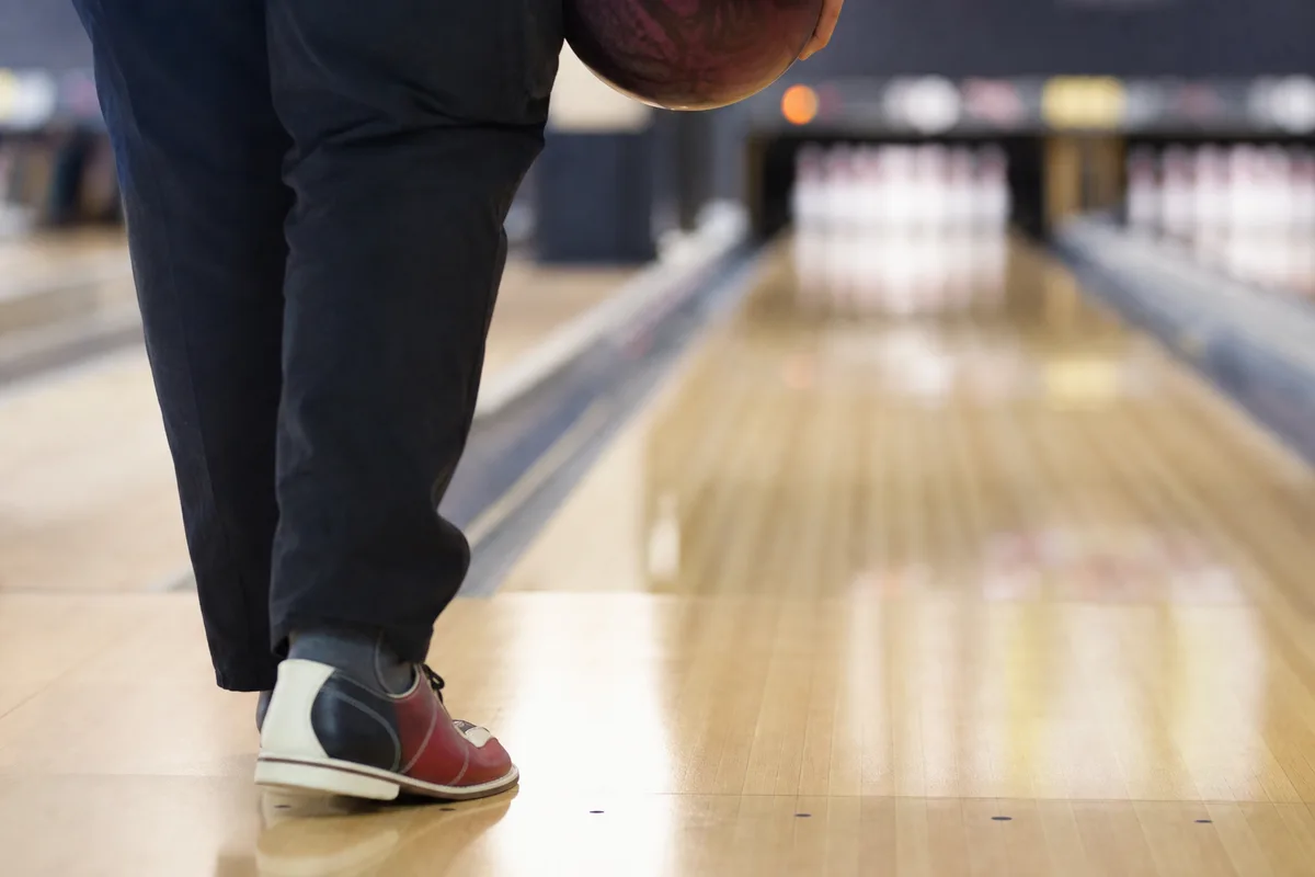 Joueur de bowling en position de départ, pieds alignés sur les points de la zone d&rsquo;élan